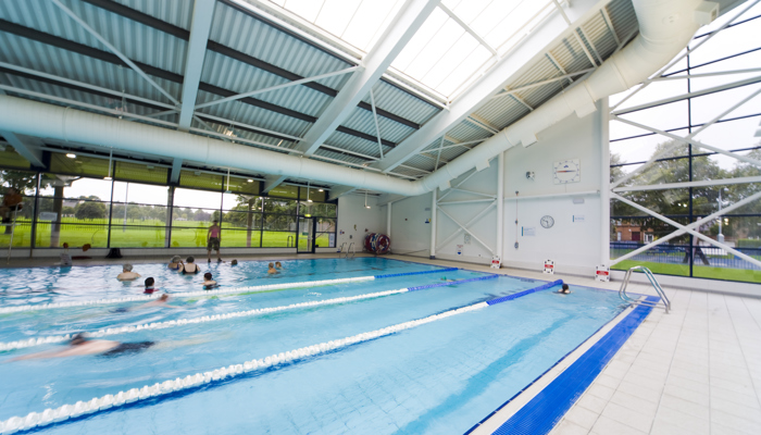 Swimmers do lengths in a public pool while others take part in a group activity