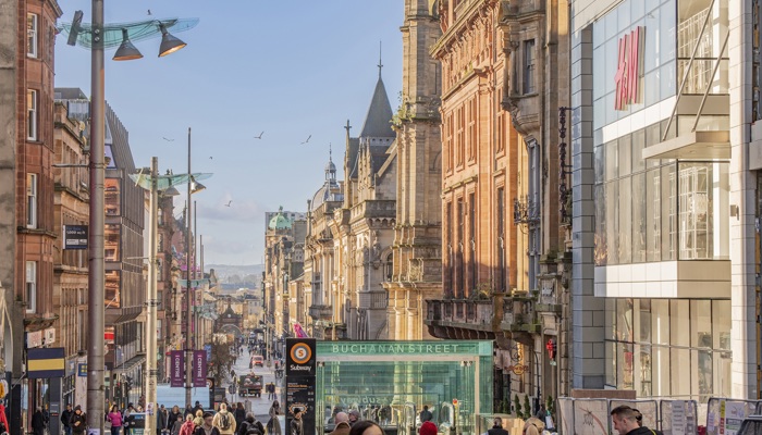 The sun shines on a busy shopping street as people walk up and down