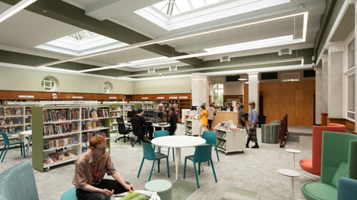 Newly refurbished interior of a historic library with large skylights. There are people reading books on armchairs, browsing bookshelves and using PCs